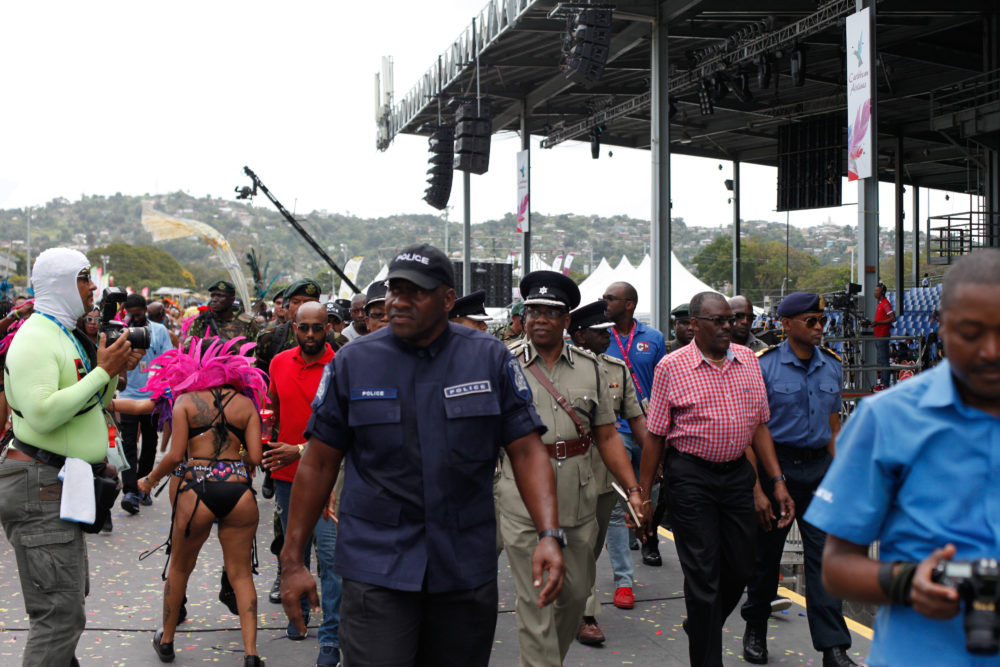 Police and army people cross the stage with a band; it's likely the Prime Minister or another important figure was playing in this band. Politicians are expected to play mas.